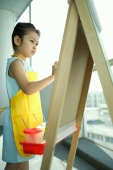 Young girl wearing apron, standing in front of easel, painting - Alex Microstock02