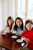 Women in cafe with cups and saucers, smiling at camera - Alex Microstock02