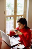 Woman using laptop, drinking from cup - Alex Microstock02