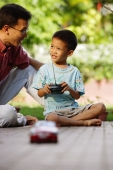 Son playing with remote control toy car, father next to him - Alex Microstock02