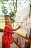 Boy pointing at drawing on easel, looking over shoulder, smiling - Alex Microstock02