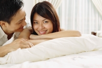 Couple in bedroom, lying on bed, woman looking at camera - Alex Microstock02