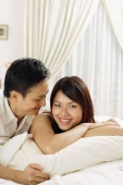 Couple in bedroom, lying on bed, woman looking at camera, man looking at her - Alex Microstock02