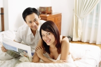 Couple in bedroom, lying on bed, looking at camera - Alex Microstock02