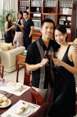 Couple at home, holding wine glasses, smiling at camera, people in the background - Alex Microstock02