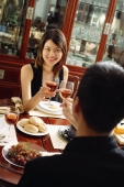 Couple toasting wine glasses across dining table - Alex Microstock02
