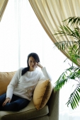 Woman in living room, sitting on sofa, looking at camera - Alex Microstock02