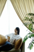 Woman in living room, sitting on sofa, looking away - Alex Microstock02