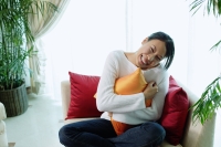 Woman hugging pillow, smiling at camera - Alex Microstock02