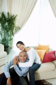 Couple in living room, woman with arm around man, looking up at camera - Alex Microstock02