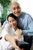 Couple in living room, woman holding remote control forward - Alex Microstock02