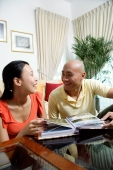 Couple at home in living room, photo album in front of them - Alex Microstock02