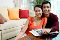 Couple at home, smiling at camera photo album in front of them - Alex Microstock02