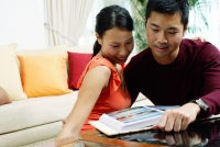 Couple at home, looking at photo album in front of them - Alex Microstock02