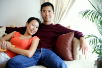 Couple in living room, sitting on sofa, smiling at camera - Alex Microstock02