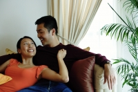 Couple sitting on sofa, woman leaning on man, looking up at him - Alex Microstock02