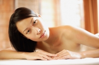 Woman lying on massage table, looking at camera - Alex Mares-Manton