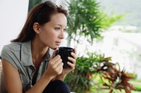 Woman holding coffee mug, looking away - Alex Mares-Manton