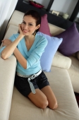 Woman sitting on sofa smiling at camera - Alex Mares-Manton