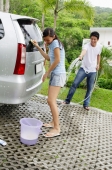 Couple washing car, man spraying woman with water - Alex Mares-Manton
