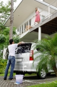 Man washing car, woman standing on balcony looking down at him - Alex Mares-Manton