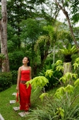 Woman in red dress, walking through garden - Alex Mares-Manton