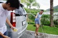 Couple washing car, woman spraying man with water, man with wet T shirt - Alex Mares-Manton