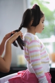 Young girl having her hair braided by mother - Nugene Chiang