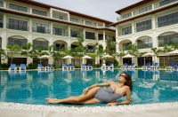Woman lying next to swimming pool, building in the background - Alex Mares-Manton