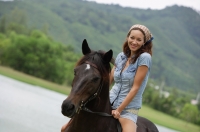 Woman sitting on horse, smiling at camera - Alex Mares-Manton