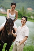 Woman sitting on horse, man standing holding reins - Alex Mares-Manton