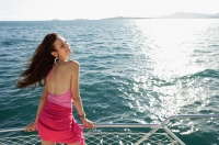 Woman on boat, standing next to railing, enjoying breeze - Alex Mares-Manton