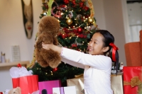 Girl sitting next to Christmas tree, holding stuffed toy - Alex Microstock02