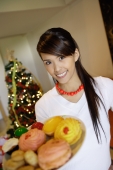 Woman holding plate of cookies, smiling at camera - Alex Microstock02