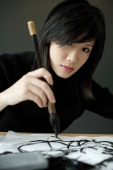 Woman holding Chinese paintbrush, painting Chinese calligraphy - Wang Leng
