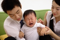 Father holding crying baby boy, mother sitting next to them - blueduck