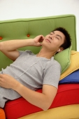 Man lying on sofa, listening to personal stereo - blueduck