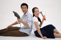 Couple sitting back to back, holding tools - blueduck