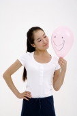 Woman looking at pink balloon, hand on hip - blueduck