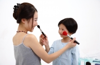 Mother and daughter applying make up on each other - blueduck
