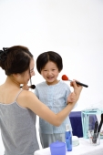 Mother and young daughter applying make-up - blueduck