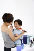 Mother and young daughter applying make-up on each other - blueduck