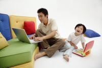 Father and daughter sitting on floor, using laptops - blueduck