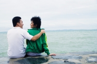 Couple sitting on breakwater, embracing, rear view - Alex Microstock02