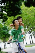 Young couple on tandem bicycle, smiling at camera - Alex Microstock02
