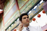 Businessman standing in front of temple gate, using mobile phone - Alex Microstock02
