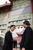 Businessmen shaking hands, temple gate in the background - Alex Mares-Manton