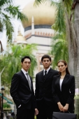 Two businessmen and one businesswoman standing together, looking at camera - Alex Mares-Manton