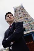 Businessman standing with arms crossed, Hindu temple in the background - Alex Microstock02