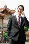 Businessman using mobile phone, standing in front of Chinese temple - Wang Leng